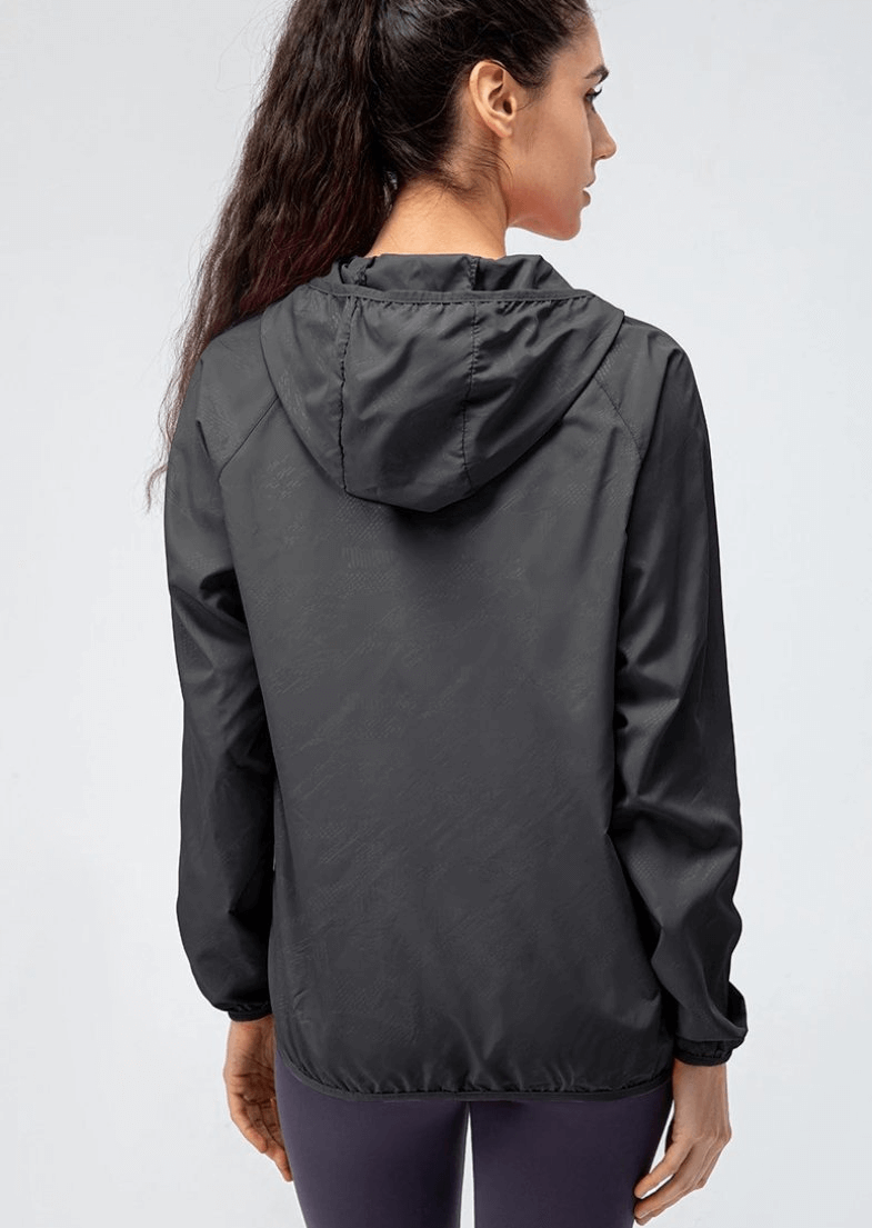Back view of woman wearing black waterproof windbreaker with hood, designed for outdoor running. Ideal for all-weather protection.
